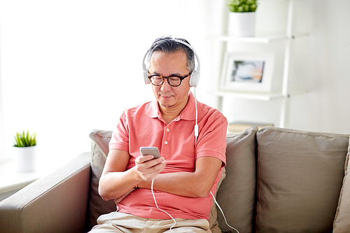 technology, people and lifestyle concept - happy man with smartphone and headphones listening to music at home