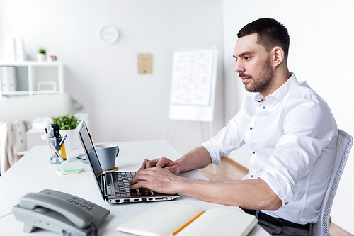 business, people and technology concept - businessman typing on laptop at office