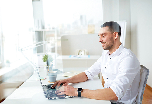 business, people and technology concept - happy smiling businessman typing on laptop computer keyboard at office