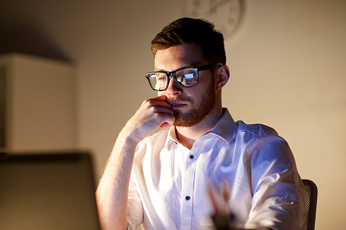 business, overwork, people, deadline and technology concept - businessman in glasses with laptop computer thinking at night office