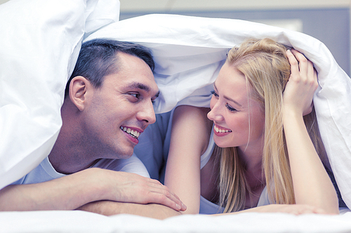 hotel, travel, relationships, and happiness concept - happy couple in bed