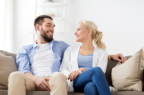 love, family and people concept - smiling happy couple sitting on sofa at home