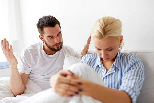 people, relationship difficulties, conflict and family concept - unhappy couple having quarrel in bed at home