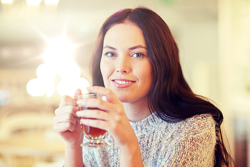 leisure, drinks, people and lifestyle concept - smiling young woman drinking tea at cafe
