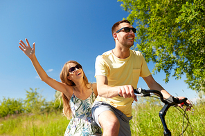 people, leisure and lifestyle concept - happy young couple riding bicycle together in summer