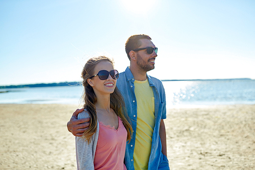 leisure, relationship and people concept - happy couple in sunglasses hugging on summer beach