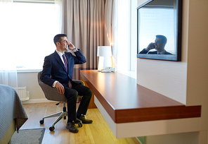 business trip, people and communication concept - businessman calling on smartphone at hotel room