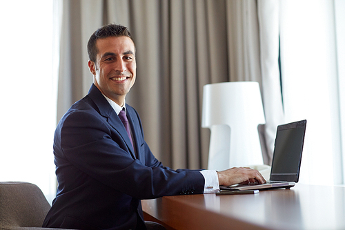 business, people and technology concept - businessman typing on laptop at hotel room