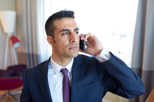 business trip, people and communication concept - businessman calling on smartphone at hotel room