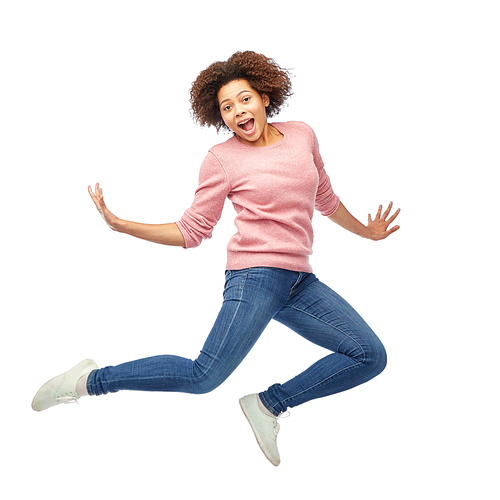 people, motion and action concept - happy african american young woman jumping over white