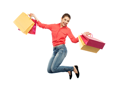 sale, motion and people concept - smiling young woman with shopping bags jumping in air over white background