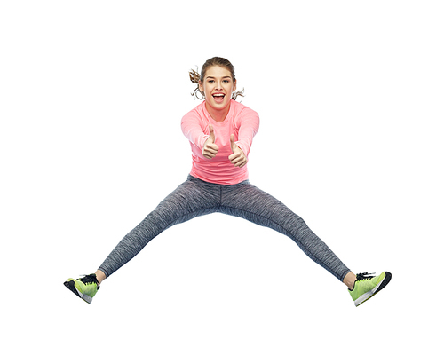 sport, fitness, motion and people concept - happy smiling young woman jumping in air over white background showing thumbs up