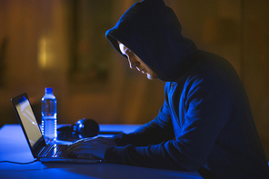 cybercrime, hacking and technology crime - male hacker in dark room using laptop computer for cyber attack