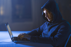 cybercrime, hacking and technology concept - male hacker with microphone using laptop computer for cyber attack or wiretapping in dark room