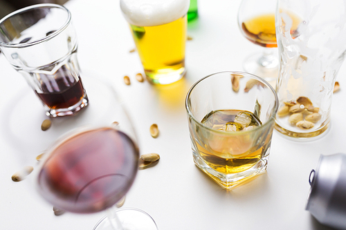 alcohol addiction and drunkenness concept - glasses of different drinks on messy table