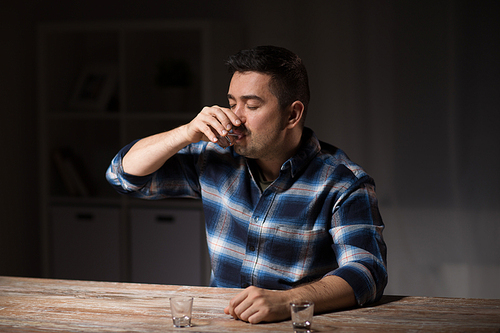 alcoholism, alcohol addiction and people concept - male alcoholic drinking shot at night