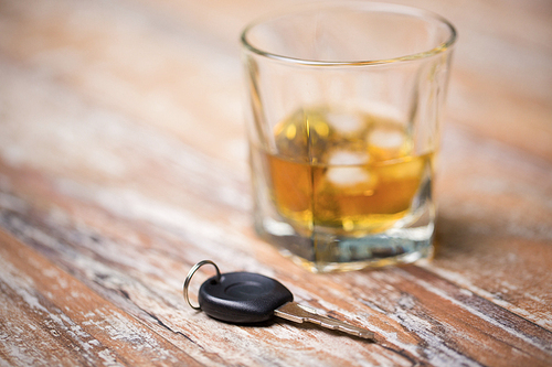 alcohol abuse, drunk driving and people concept - close up of whiskey glass and car key on table