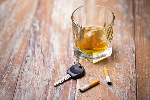 alcohol abuse, drunk driving and people concept - close up of whiskey glass and car key on table