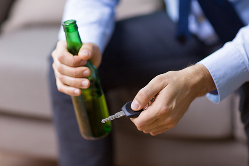 alcohol abuse, drunk driving and people concept - close up of male driver hands holding beer bottle and car key