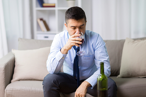 alcoholism, alcohol addiction and people concept - male alcoholic drinking glass of red wine at home