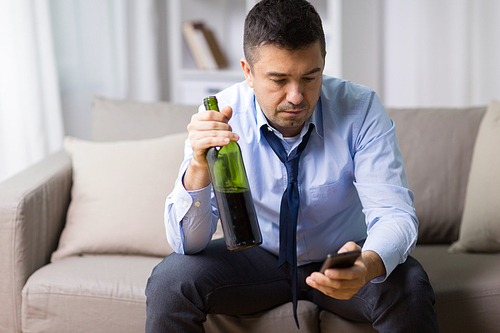 alcoholism, alcohol addiction and people concept - drunk man with smartphone and bottle of wine at home