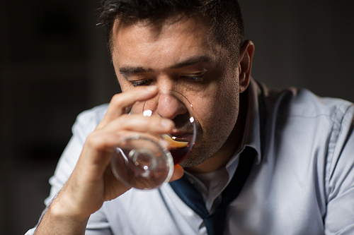 alcoholism, alcohol addiction and people concept - close up of male alcoholic drinking brandy at night