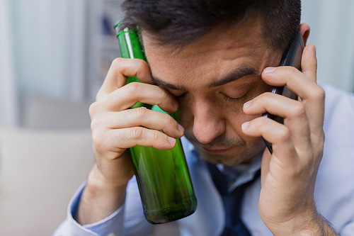 alcoholism, alcohol addiction and people concept - close up of male alcoholic drinking beer and calling on smartphone at home