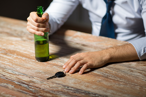 alcohol abuse, drunk driving and people concept - close up of male driver hands with beer bottle and car key on table