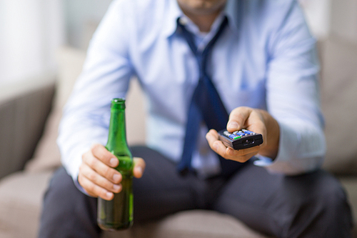 alcoholism, alcohol addiction and people concept - close up of man with tv remote drinking beer