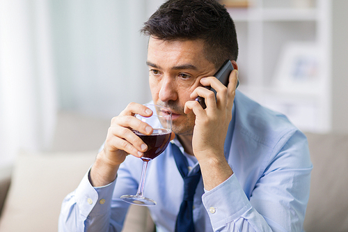 alcoholism, alcohol addiction and people concept - male alcoholic drinking wine and calling on smartphone at home