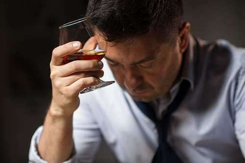 alcoholism, alcohol addiction and people concept - close up of male alcoholic drinking brandy at night