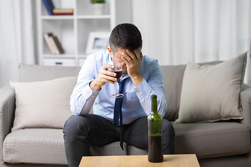 alcoholism, alcohol addiction and people concept - male alcoholic drinking glass of red wine at home