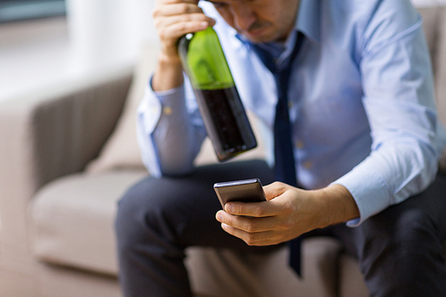 alcoholism, alcohol addiction and people concept - close up of drunk man with smartphone and bottle of wine at home