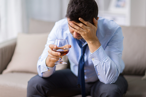 alcoholism, alcohol addiction and people concept - male alcoholic drinking brandy at home