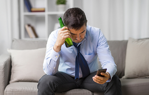 alcoholism, alcohol addiction and people concept - drunk man with smartphone and bottle of beer at home