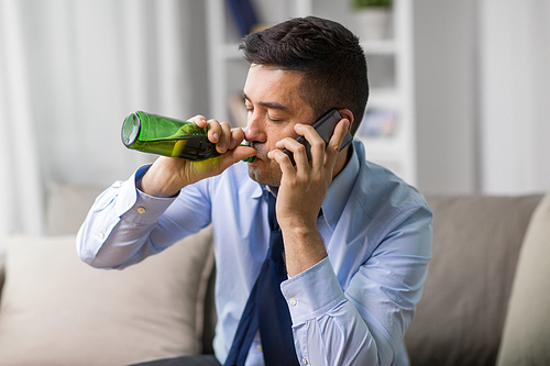 alcoholism, alcohol addiction and people concept - male alcoholic drinking beer and calling on smartphone at home