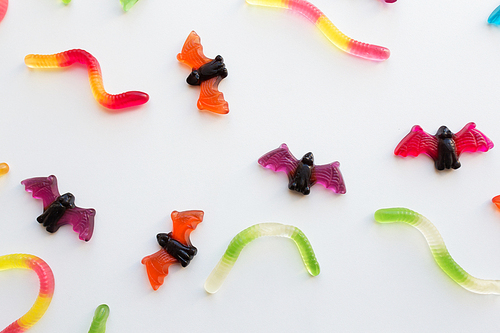 halloween, junk food and confectionery concept concept - multicolored gummy worms and bet candies over white background