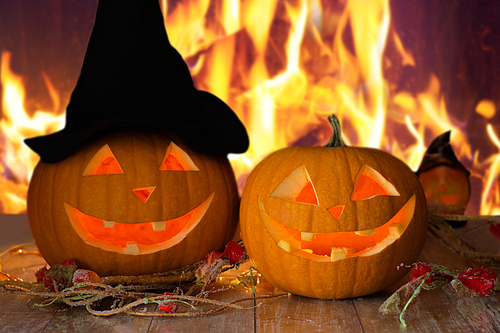 holidays, halloween and decoration concept - carved pumpkins on table over fire background