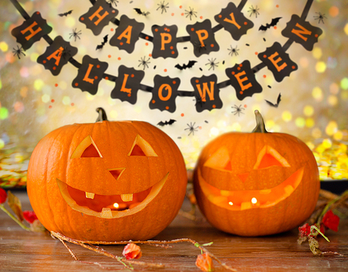 holidays, decoration and celebration concept - jack-o-lantern or pumpkins and happy halloween festive garland or banner over lights background