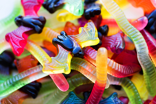 halloween, junk food and confectionery concept concept - heap of multicolored gummy worms and jelly bet candies