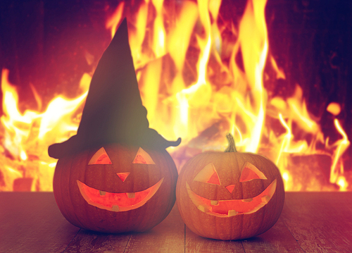 holidays, halloween and decoration concept - carved pumpkins on table over fire background