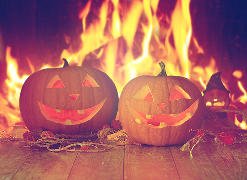 holidays, halloween and decoration concept - carved pumpkins on table over fire background