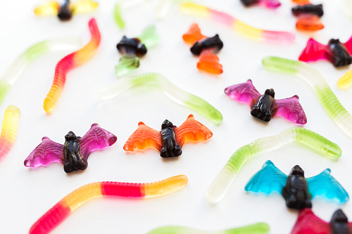 halloween, junk food and confectionery concept concept - multicolored gummy worms and jelly bet candies over white background