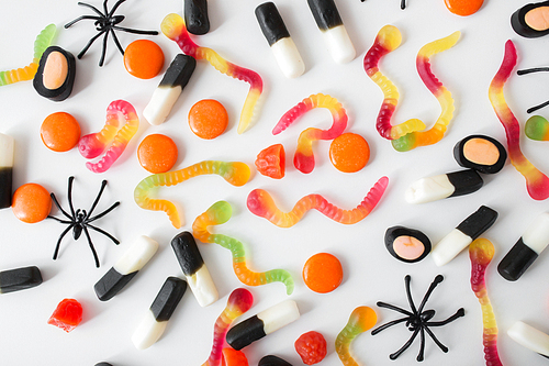 halloween, junk food and confectionery concept concept - multicolored gummy worms and jelly candies over white background