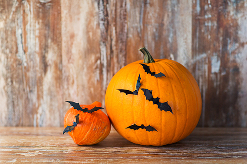 halloween and holidays concept - pumpkins with bats or party decorations