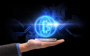 business, cryptocurrency and future technology concept - close up of male hand holding smartphone with virtual bitcoin symbol hologram over black background