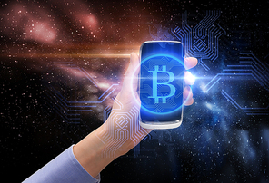 business, cryptocurrency and future technology concept - close up of female hand holding smartphone with virtual bitcoin symbol hologram over space background