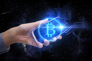 business, cryptocurrency and future technology concept - close up of female hand holding smartphone with virtual bitcoin symbol hologram over black background