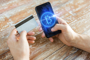 business, technology and cryptocurrency concept - close up of male hand holding smartphone with bitcoin on screen and credit card