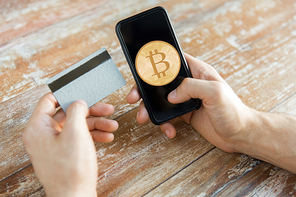 business, technology and cryptocurrency concept - close up of male hand holding smartphone with bitcoin on screen and credit card